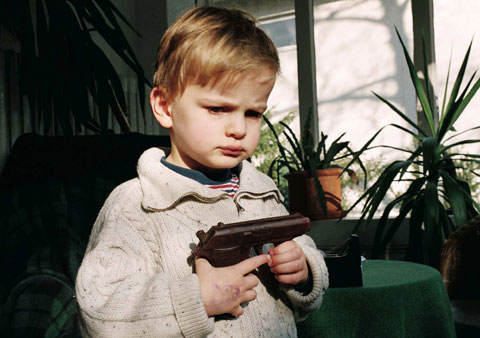 Photo of a child with chocolate gun in hands. 1 x 0,7m print, by YLS Yvonne Lee Schultz 