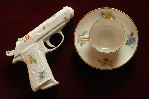 Carl Walther's James Bond PPK replica in Porcelain by YLS. Close to mocca cup with scattered flowers 